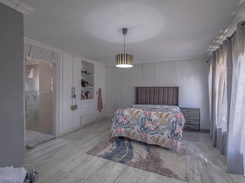 Spacious bedroom featuring built-in cupboards, crown molding, laminate flooring, and direct access to an en-suite bathroom.