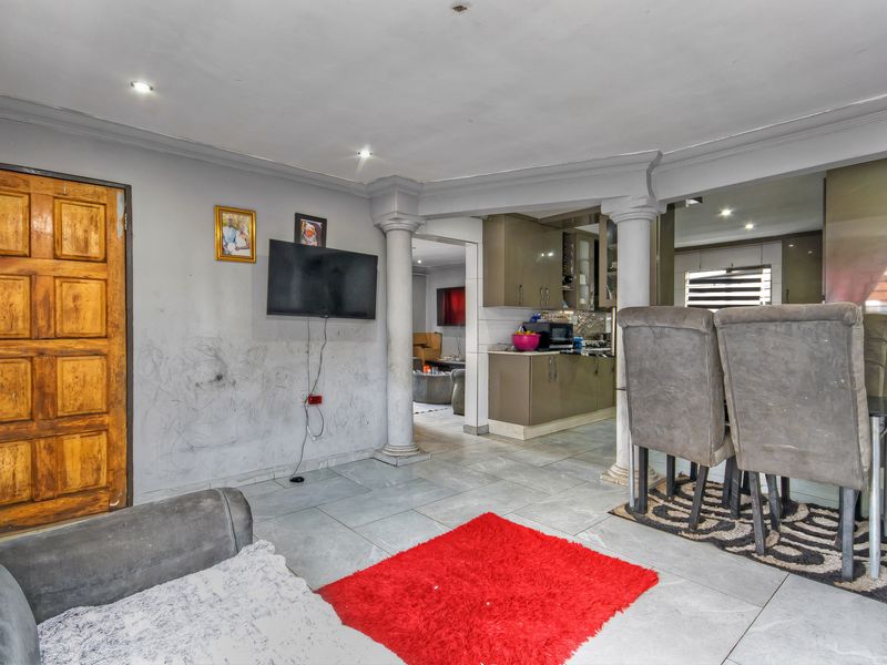 Open plan living and kitchen area featuring tiled flooring, decorative columns, and built-in cabinetry, requiring cosmetic wall repairs to restore the space.