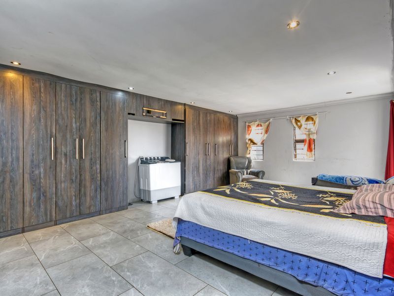 Spacious bedroom featuring extensive built-in wooden cupboards, tiled flooring, and recessed ceiling lighting, offering ample storage and a neutral foundation.