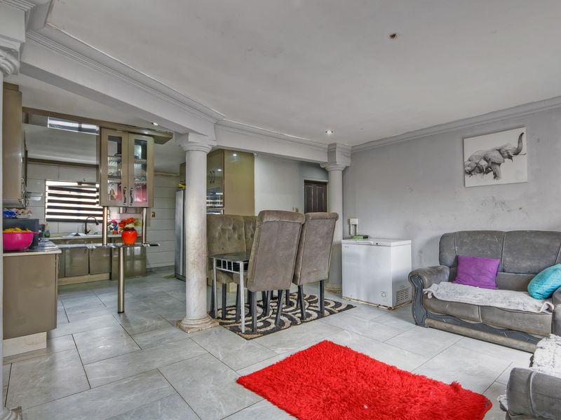 Open-plan living and kitchen area featuring tiled flooring, decorative columns, and built-in cabinetry, offering a versatile space for dining and relaxation.