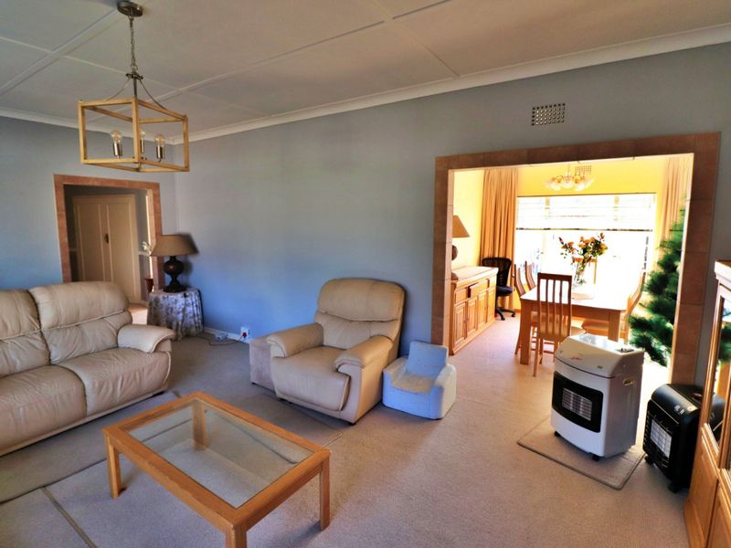 Open plan living and dining area featuring neutral wall tones, tiled archway transitions, and classic ceiling coving.