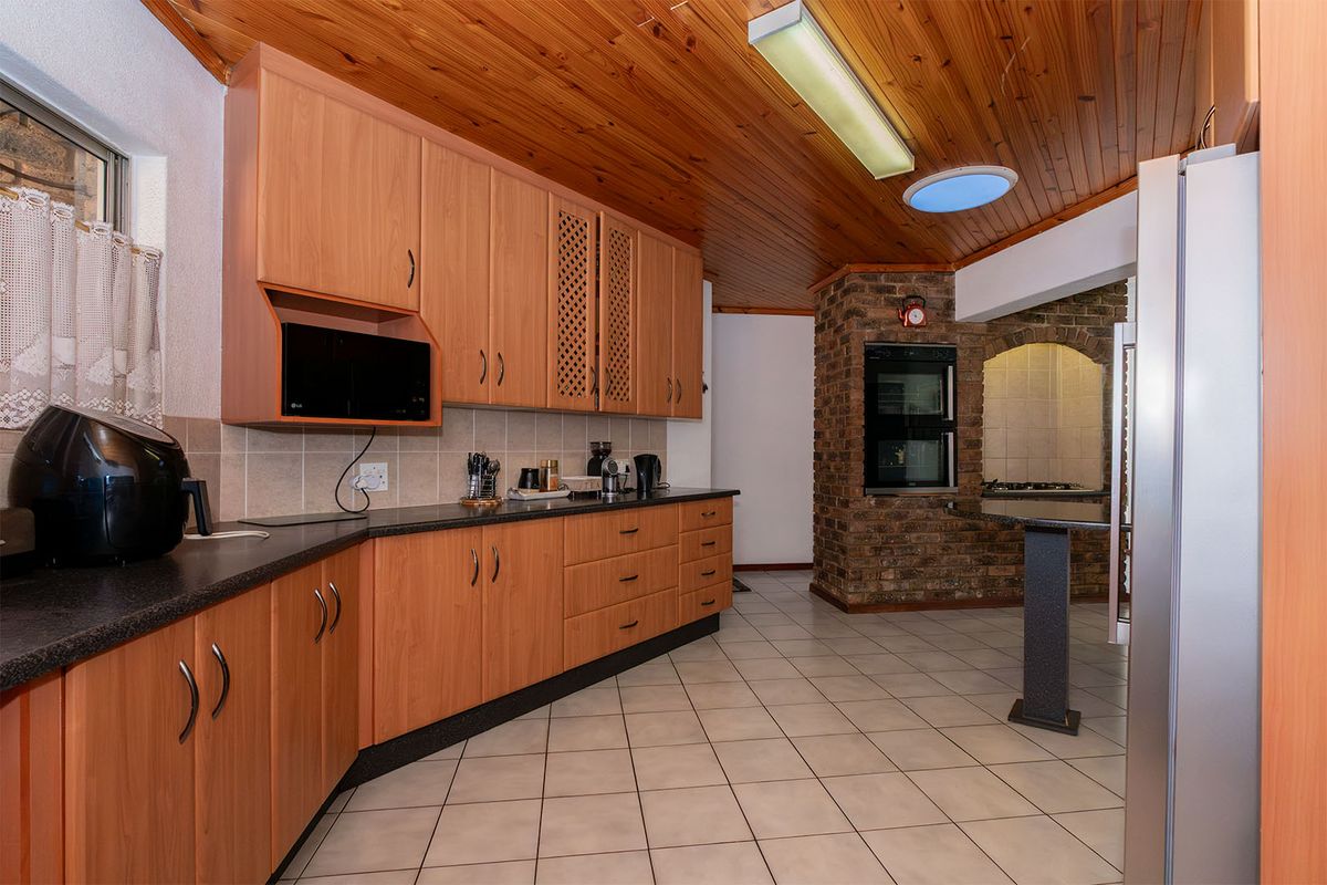 A functional kitchen featuring timber ceilings, exposed brickwork, built-in double oven, and ample cabinetry, offering a dated aesthetic ready for modern updates.