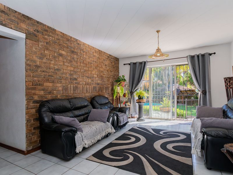Living room featuring an exposed brick wall, tiled flooring, and a sliding glass door providing access to the outdoor area.