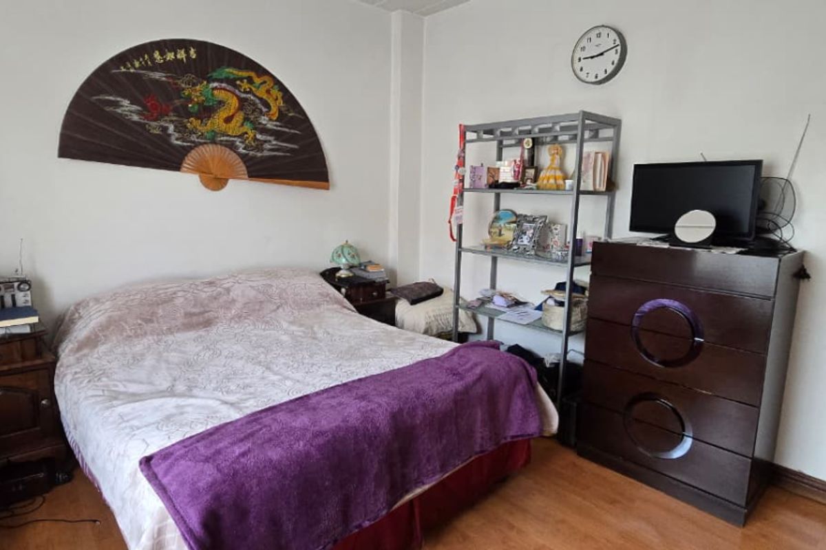 A standard bedroom featuring laminate flooring and neutral wall finishes, providing a functional space with direct access to an adjacent bathroom.