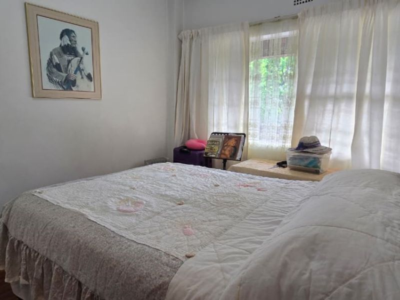 A standard bedroom featuring laminate flooring and window curtain tracks, providing a functional space for rest.