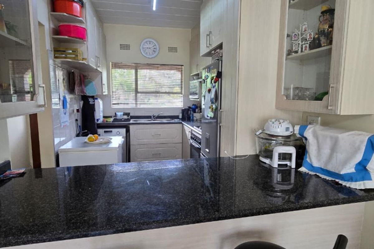 A functional kitchen featuring granite countertops, ample built-in cabinetry, and a double sink, offering a practical layout for daily meal preparation.