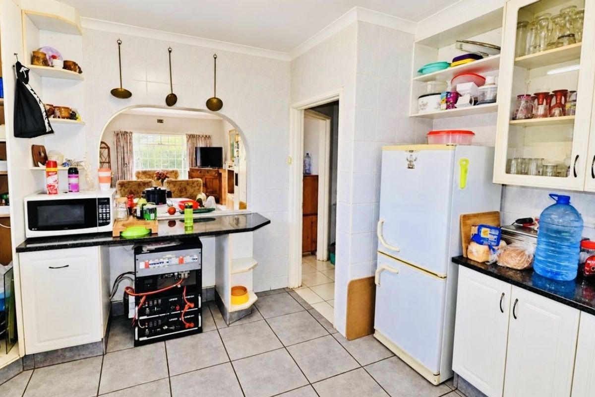 Functional kitchen featuring granite countertops, ample built-in cabinetry, and tiled flooring, with an open archway connecting to the adjacent living area.