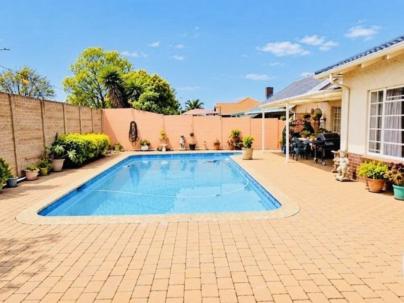 A well-maintained outdoor pool area featuring a paved patio, swimming pool, and secure boundary walls, ideal for outdoor relaxation and entertainment.