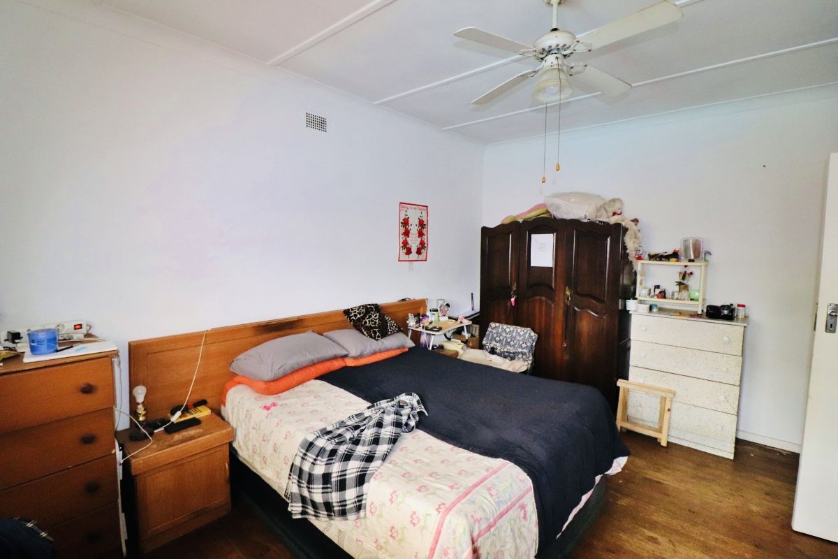 A functional bedroom featuring timber flooring and a ceiling fan, offering a neutral base for potential interior updates.