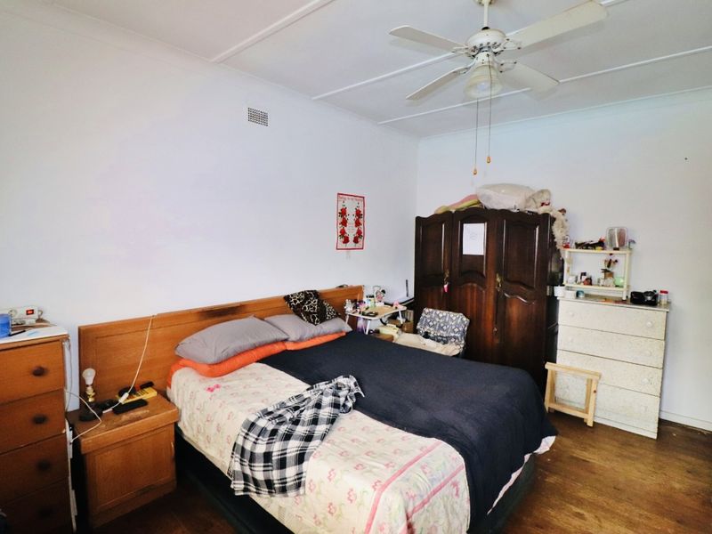 A functional bedroom featuring timber flooring and a ceiling fan, offering a neutral base for potential interior updates.