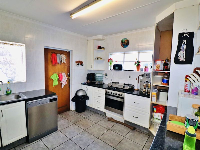 A functional kitchen featuring built-in cabinetry, a gas hob, an oven, and tiled surfaces throughout, offering a practical layout for daily meal preparation.