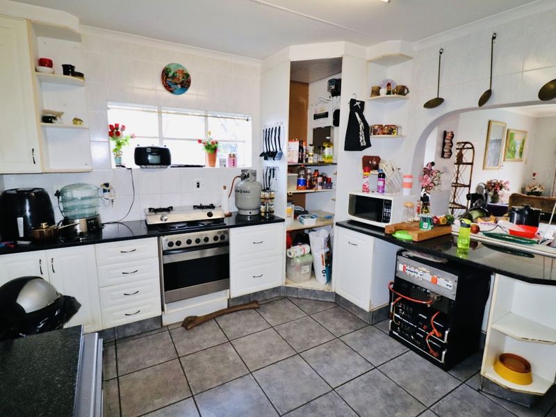 Functional kitchen featuring granite countertops, gas stove, oven, and tiled finishes, with an open-plan layout connecting to the adjacent living area.