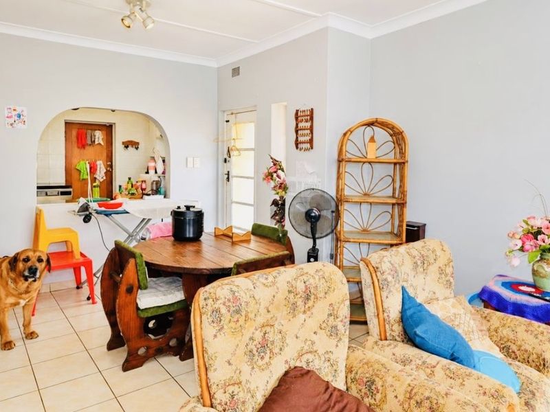 Open plan living and dining area featuring tiled flooring, coved ceilings, and an arched transition to the kitchen space.
