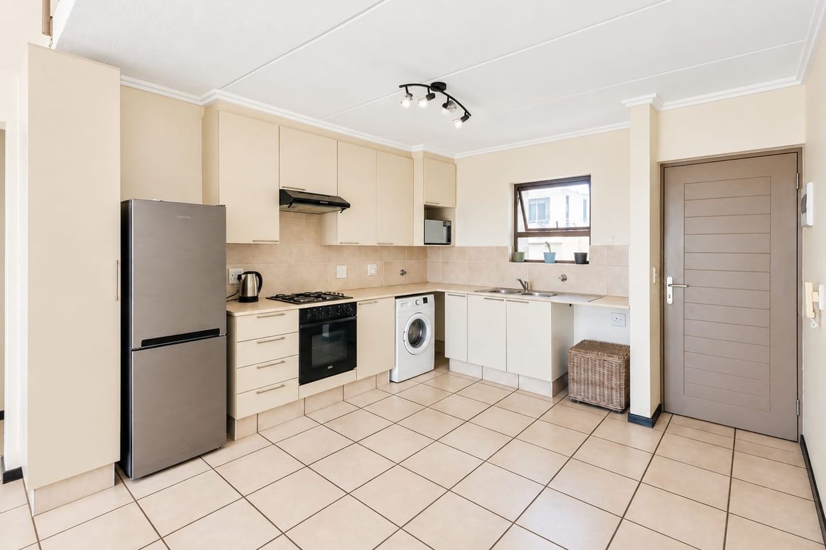 A functional kitchen featuring tiled flooring, built-in cabinetry, a gas hob with extractor fan, and a double sink with a tiled backsplash.