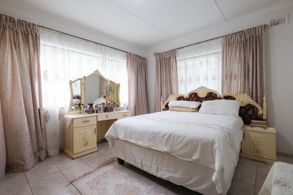 A well-lit bedroom featuring tiled flooring and dual windows with curtain rails, offering a neutral foundation for interior updates.