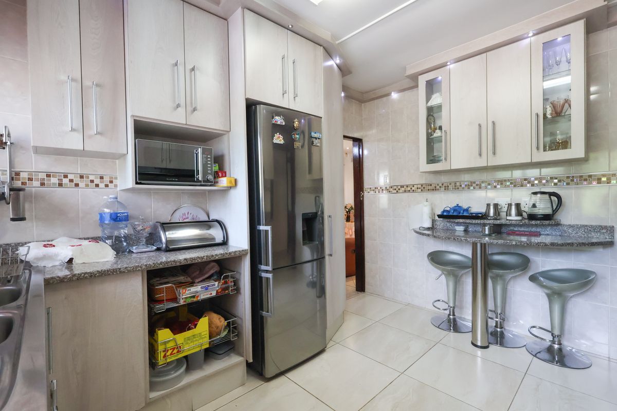 A functional kitchen featuring light wood cabinetry, granite countertops, a tiled backsplash, and a convenient breakfast bar area with recessed lighting.