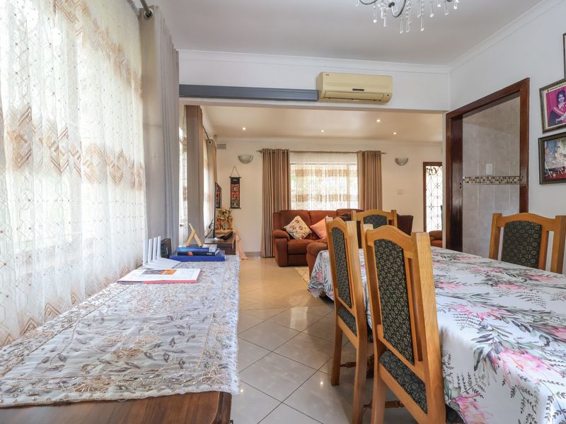Spacious open-plan living and dining area featuring tiled flooring, recessed lighting, and a wall-mounted air conditioning unit.