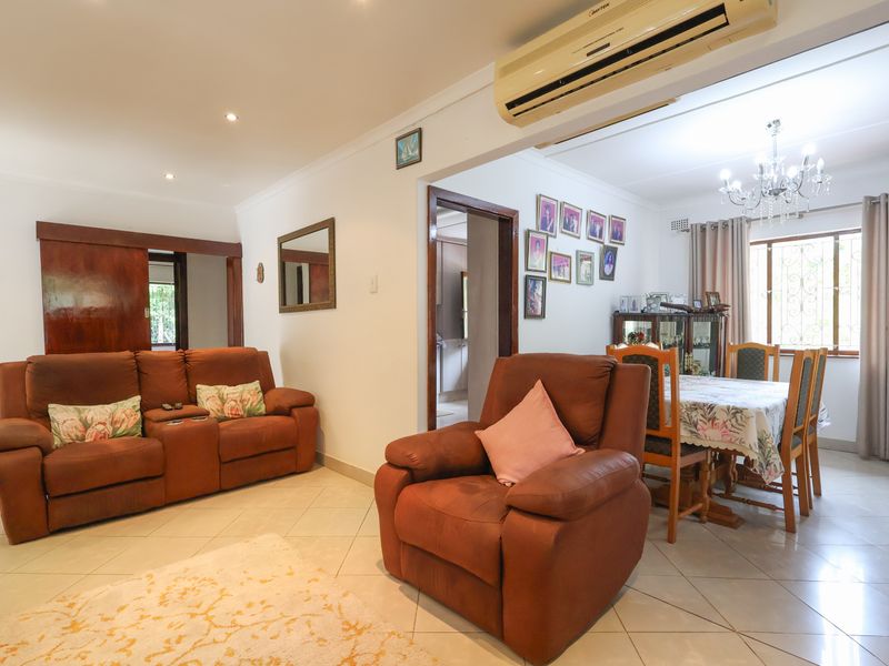 Open-plan living and dining area featuring ceramic floor tiles, recessed downlighting, and a wall-mounted split-system air conditioner.