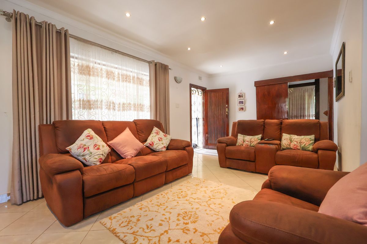A bright and spacious living room featuring tiled flooring, recessed downlighting, and built-in wooden cabinetry, providing a comfortable and functional living space.