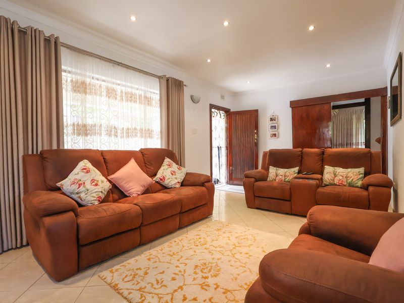 A bright and spacious living room featuring tiled flooring, recessed downlighting, and built-in wooden cabinetry, providing a comfortable and functional living space.