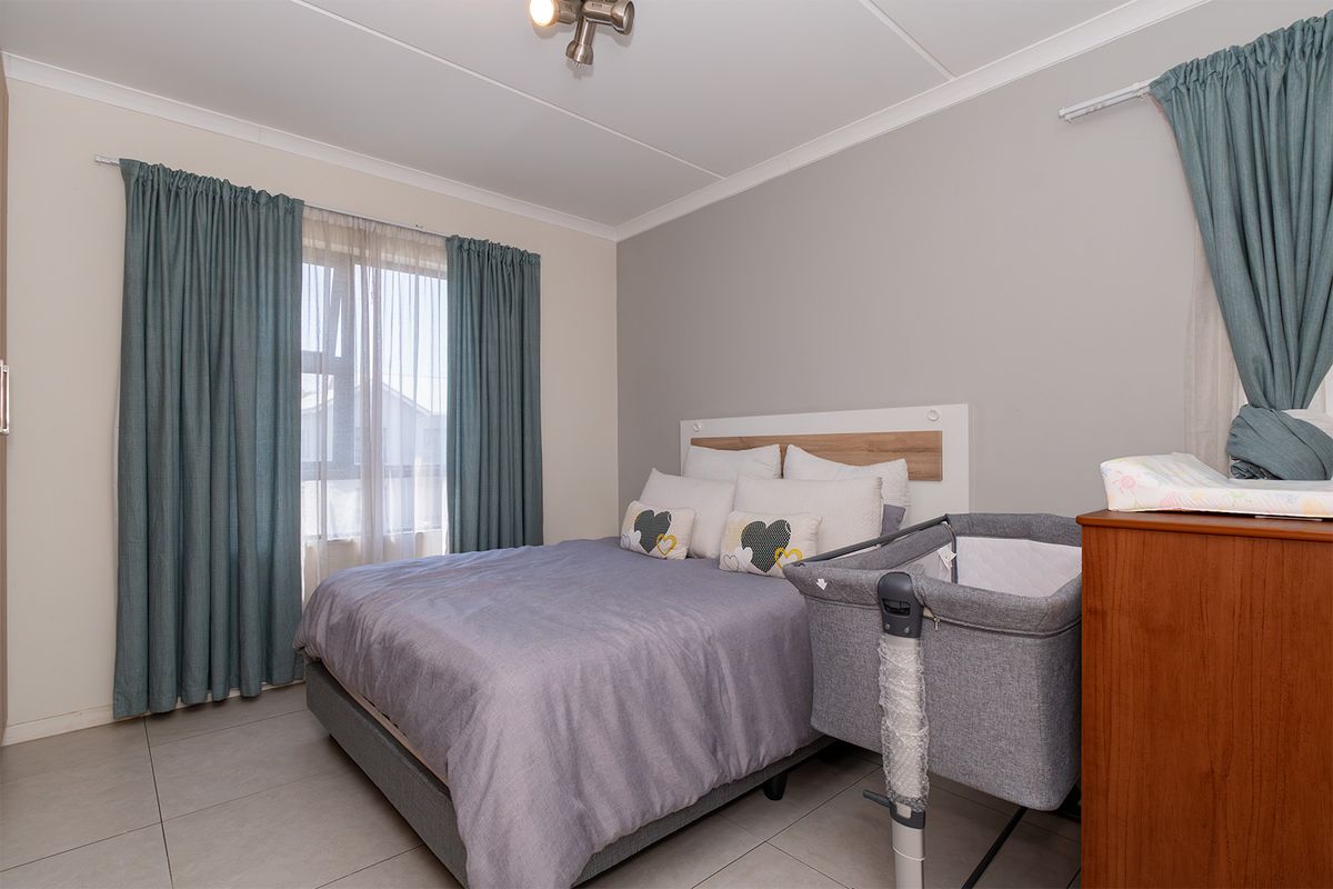 A well-maintained bedroom featuring neutral wall tones, tiled flooring, and a built-in headboard, offering a comfortable and functional living space.