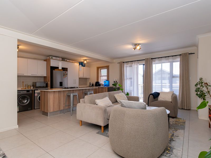 Spacious open-plan living area featuring a modern kitchen with island, tiled flooring, and large sliding doors providing natural light and access to the exterior.