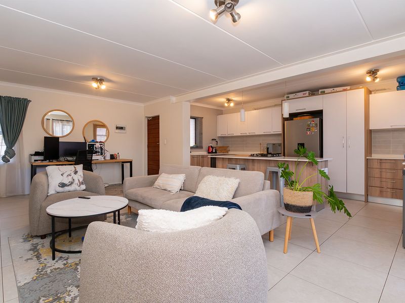 Spacious open-plan living area featuring a modern kitchen with built-in cabinetry, a central island, and tiled flooring throughout.