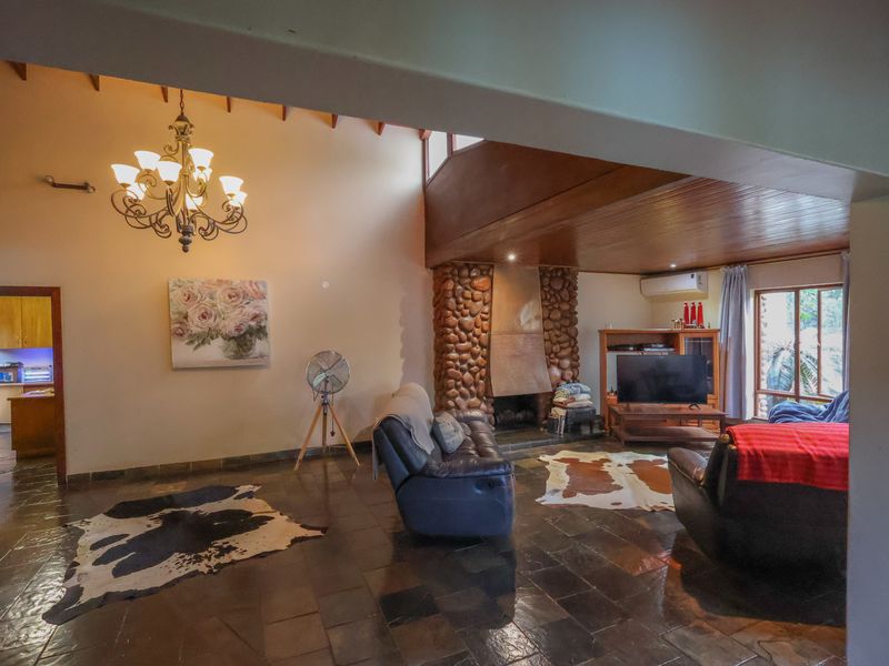 Spacious living room featuring a unique stone fireplace, slate tile flooring, and an exposed timber ceiling, creating a warm and rustic atmosphere.