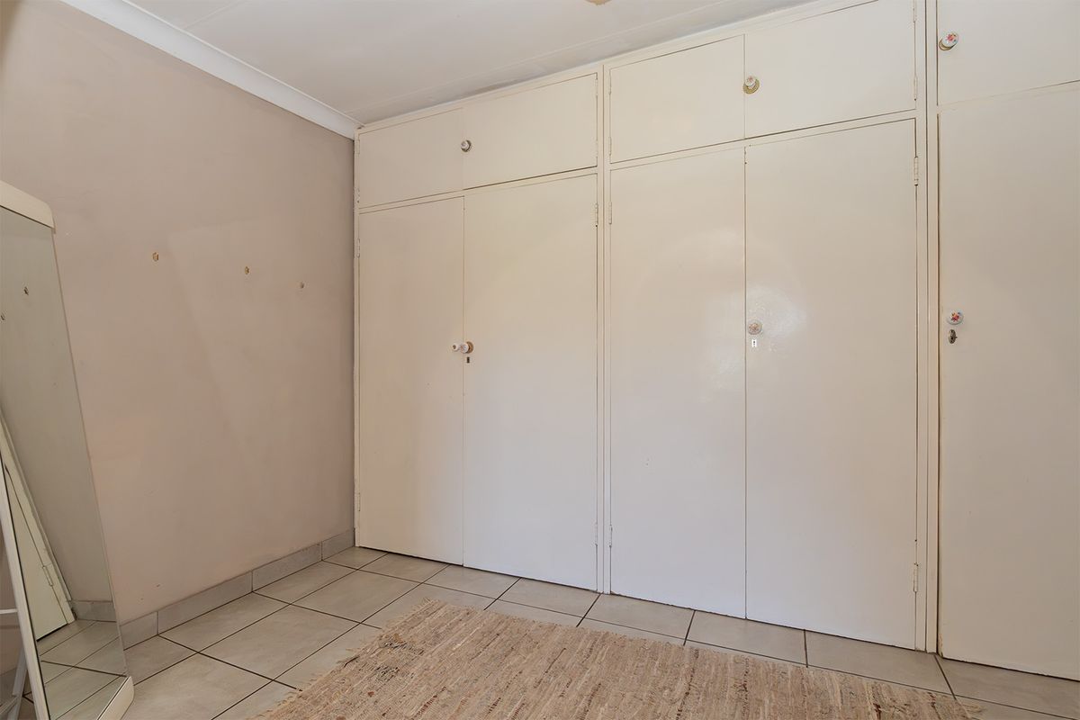 A bedroom featuring tiled flooring and extensive built-in cupboards with overhead storage compartments.