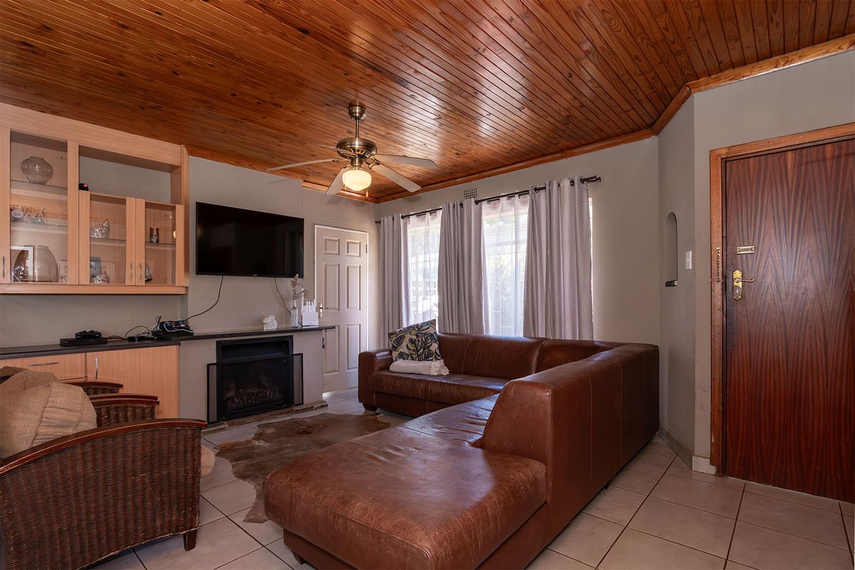 A cozy living room featuring a warm timber ceiling, built-in cabinetry, a fireplace, and tiled flooring, creating a comfortable and inviting atmosphere.
