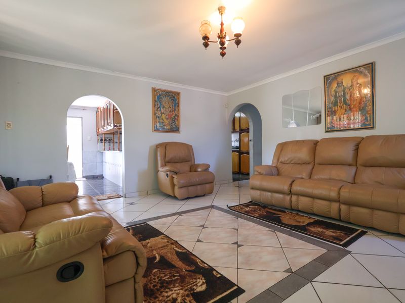 Spacious living room featuring tiled flooring, coved ceilings, and arched doorways leading to adjacent areas of the home.
