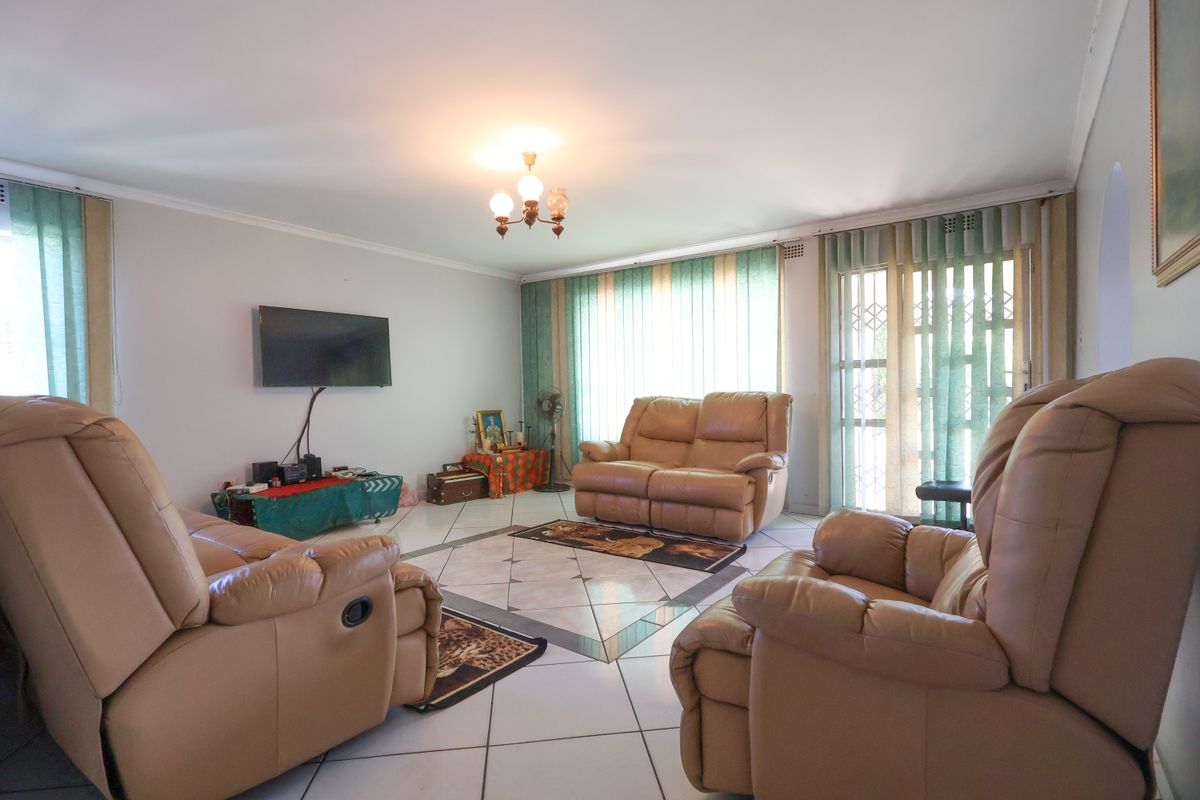 Spacious living room featuring tiled flooring, large sliding glass doors with vertical blinds, and a central ceiling light fixture.