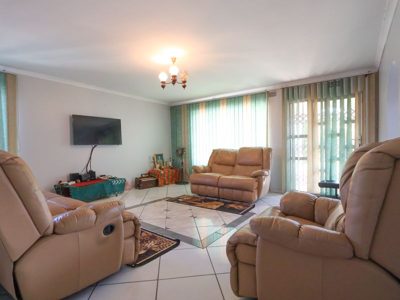 Spacious living room featuring tiled flooring, large sliding glass doors with vertical blinds, and a central ceiling light fixture.