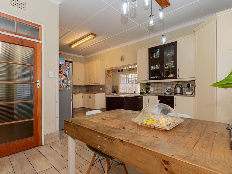 A functional kitchen featuring ample built-in cabinetry, tiled backsplash, and tiled flooring, offering a practical layout for daily meal preparation.