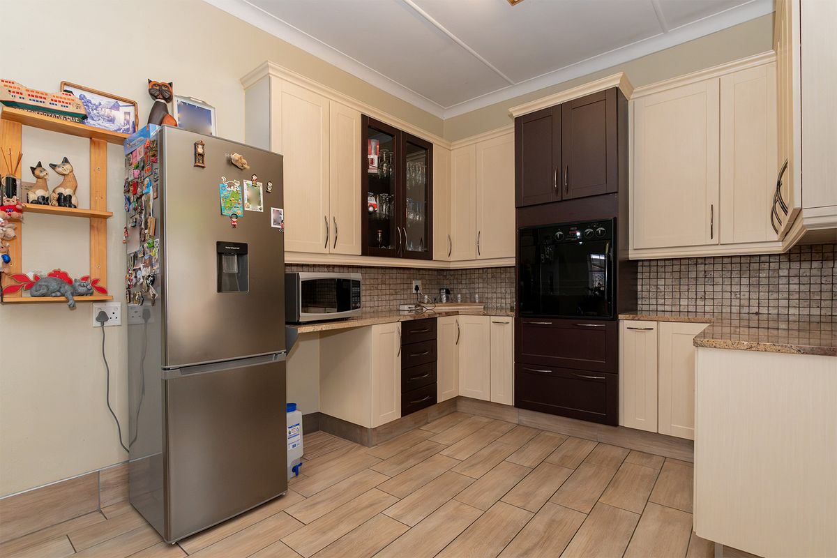 A functional kitchen featuring two-tone cabinetry, granite countertops, a built-in oven, and tiled flooring, offering a practical layout for daily meal preparation.