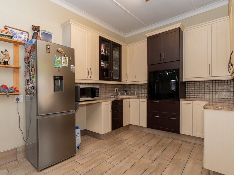 A functional kitchen featuring two-tone cabinetry, granite countertops, a built-in oven, and tiled flooring, offering a practical layout for daily meal preparation.