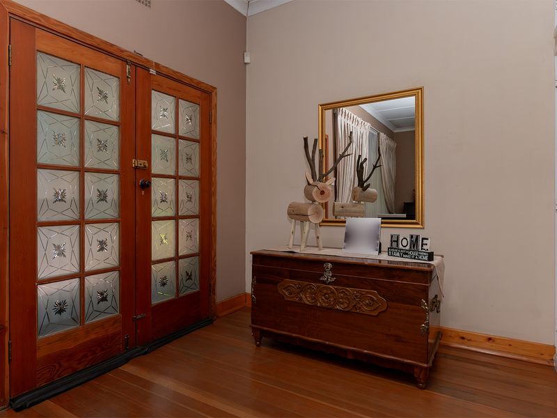 Welcoming entrance hall featuring classic timber double doors with leaded glass inserts and warm timber flooring.