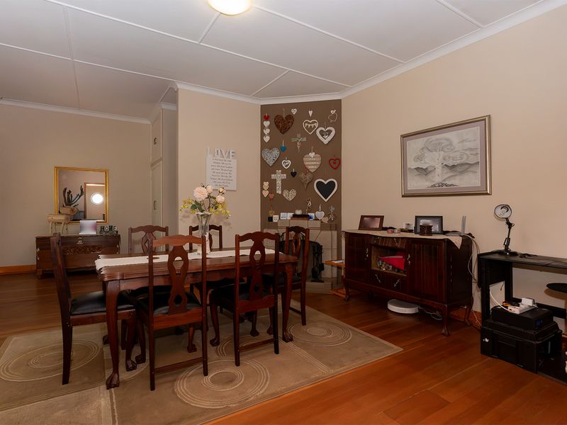 A dining room featuring hardwood flooring, a coved ceiling, and a corner fireplace, providing a functional space for family meals.