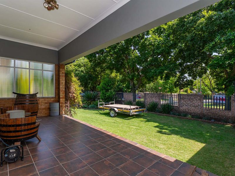 A covered patio area with tiled flooring overlooking a private garden with a brick boundary wall.