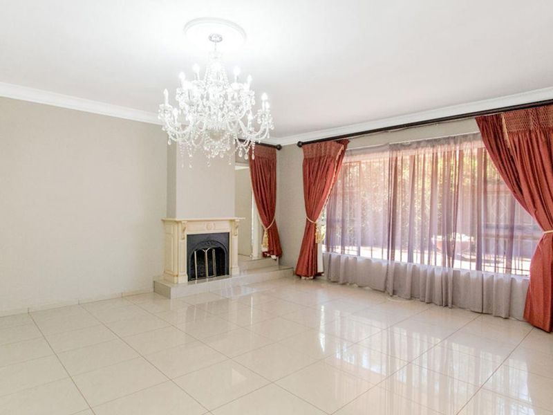 Spacious living room featuring polished tile flooring, a classic fireplace, and an elegant crystal chandelier, offering a bright and neutral canvas for your design.