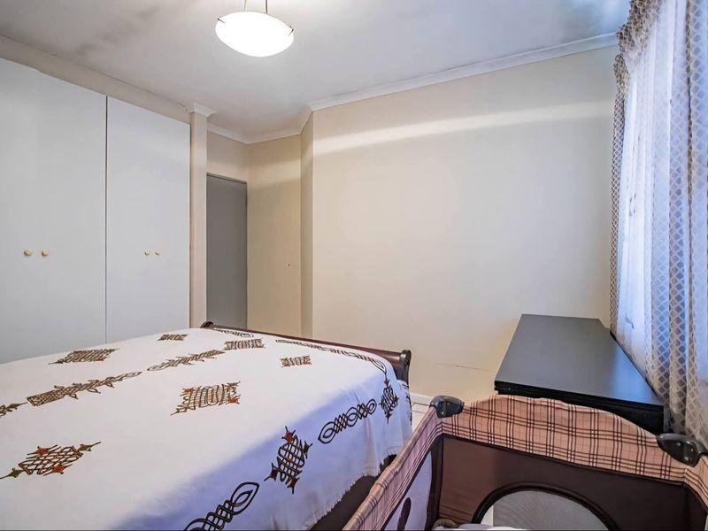A bedroom featuring built-in cupboards and coved ceilings, showing visible signs of water staining on the ceiling.