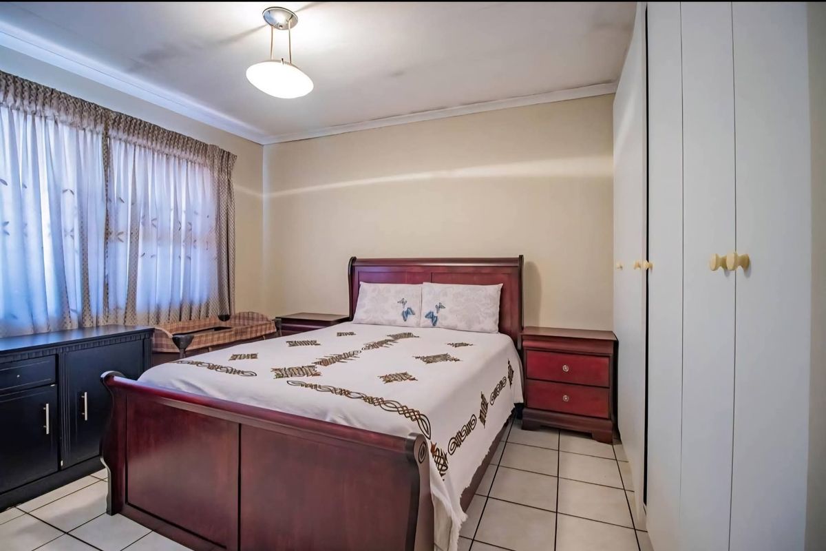 A bedroom featuring tiled flooring, built-in cupboards, and a ceiling light fixture. Note visible water staining on the ceiling.
