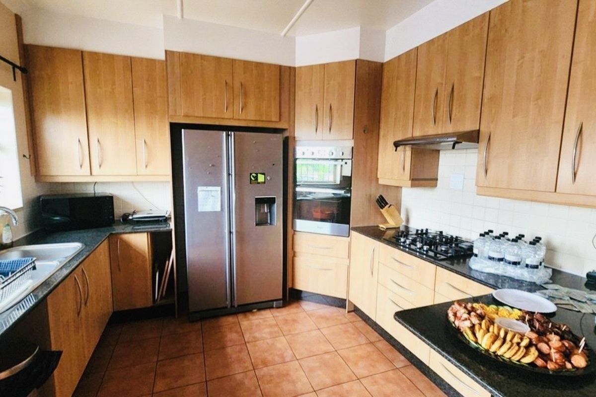 A functional kitchen featuring wooden cabinetry, granite countertops, a built-in double oven, gas hob, and tiled flooring.