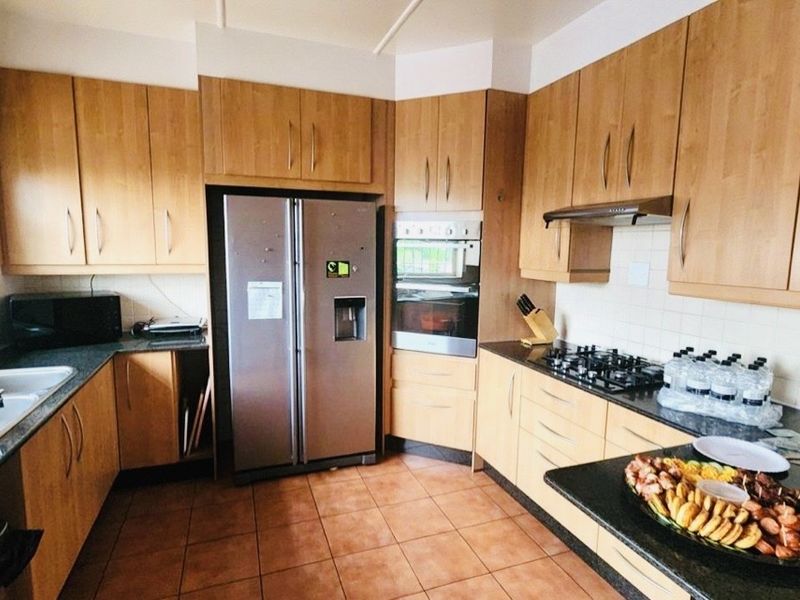 A functional kitchen featuring wooden cabinetry, granite countertops, a built-in double oven, gas hob, and tiled flooring.