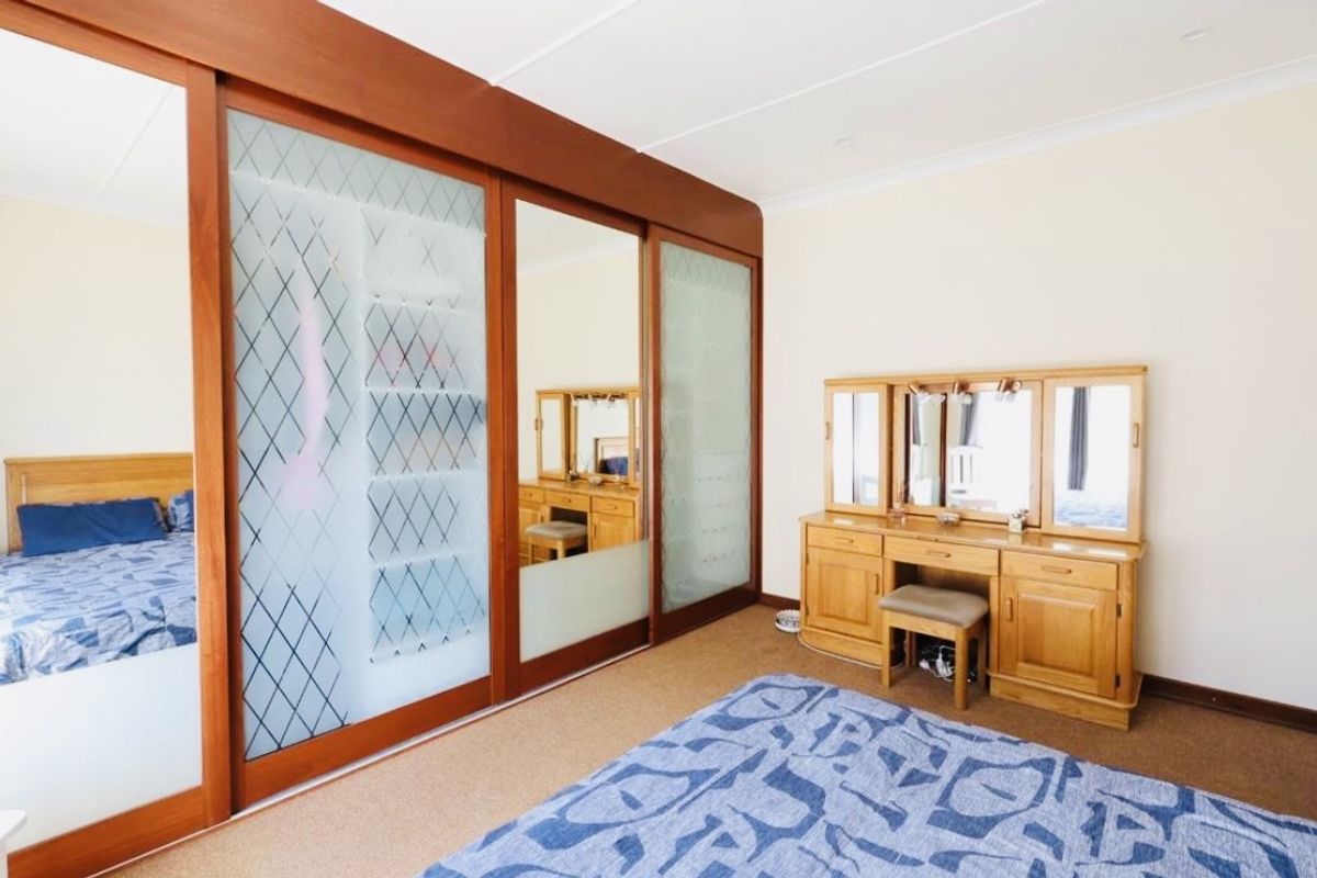 A bedroom featuring a large built-in wardrobe with sliding glass and wood doors, carpeted flooring, and coved ceiling details.