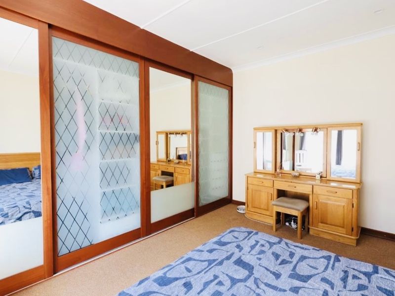 A bedroom featuring a large built-in wardrobe with sliding glass and wood doors, carpeted flooring, and coved ceiling details.