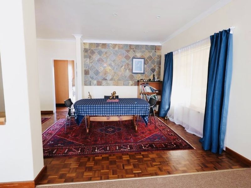 Dining room featuring classic parquet flooring and a decorative stone feature wall, offering a warm and traditional aesthetic.