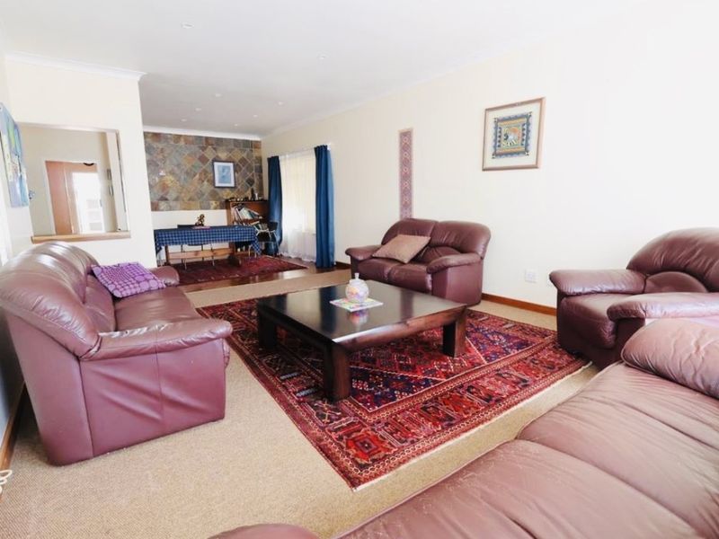 Spacious open-plan living and dining area featuring a stone accent wall, neutral carpeting, and recessed lighting, offering a versatile layout for family living.