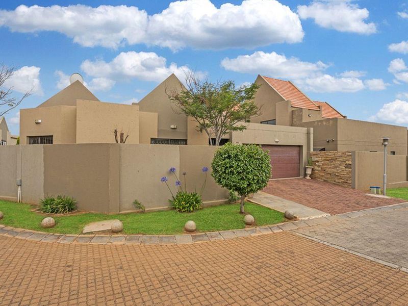 Front elevation of a modern residential house featuring a paved driveway, double garage, and well-maintained garden with boundary walling.