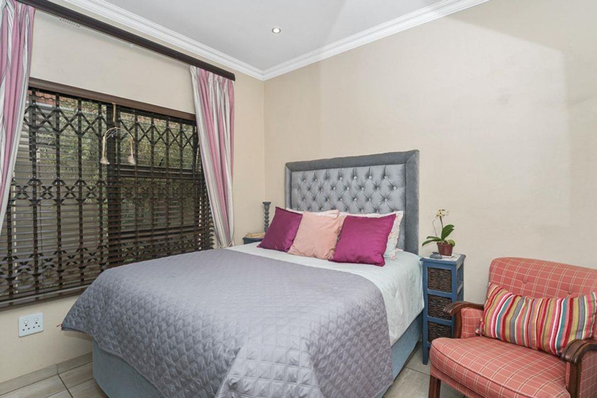 A comfortable bedroom featuring tiled flooring, recessed downlighting, decorative cornicing, and a window fitted with a security gate.
